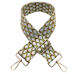 Close-up of jacquard wide strap with peacock pattern and golden metal lobster clasps