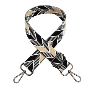 Macro view of adjustable woven bag strap with black and white chevron pattern and metal hooks