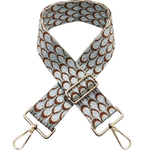 Detail of woven jacquard purse strap with peacock pattern and gold metal buckles