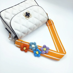 Detail of wide orange woven bag strap with colorful handmade crochet flowers