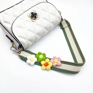 White quilted crossbody bag with floral buckle and colorful crochet flower strap