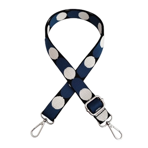 Close-up of wide navy blue knit strap with large white polka dots and silver metal hooks