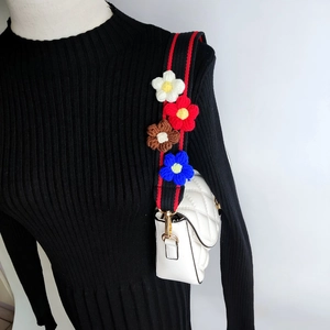 Detail of colorful crochet flower shoulder strap on a quilted white crossbody bag
