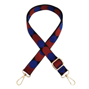 Close-up of adjustable bag strap with red and blue dot patterns and gold metal hooks
