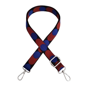 Detail of adjustable bag strap with red and blue polka dots and silver metal hooks