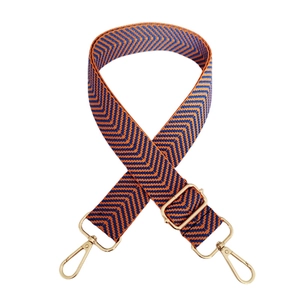 Detail of orange and blue herringbone woven wide bag strap with gold metal hooks