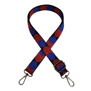 Adjustable bag strap with red and blue polka dot patterns and black hardware