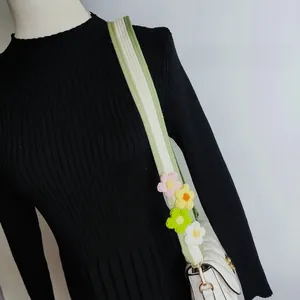 Detail of colorful floral crochet strap on a white quilted crossbody bag with gold clasps