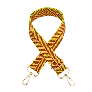 Close-up of wide red and yellow herringbone woven bag strap with gold metal hooks