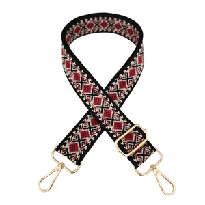 Close-up of geometric diamond jacquard bag strap with golden lobster clasps