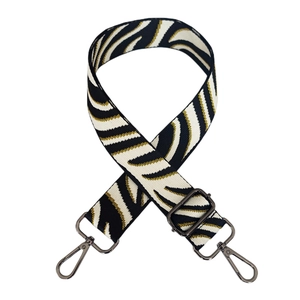 Macro detail of zebra pattern woven bag strap with gunmetal adjustable buckles