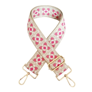 Macro detail of pink and beige geometric jacquard woven strap with golden metal hooks
