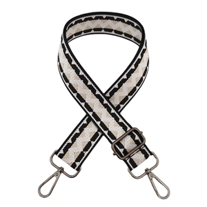 Macro view of adjustable wide woven bag strap with bronze hooks and wave pattern