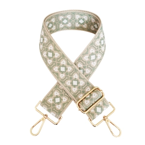 Close-up of jacquard woven geometric bag strap in light green and beige with gold metal clips