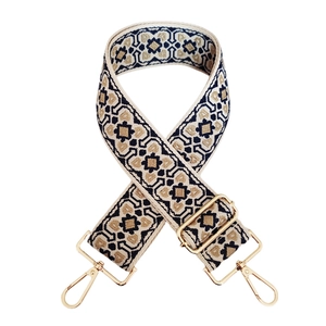 Detail of adjustable wide purse strap with geometric jacquard pattern and gold buckles
