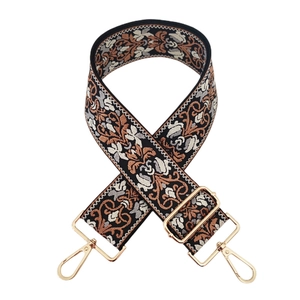 Detail of vintage floral embroidered wide strap with gold metal buckles on white background