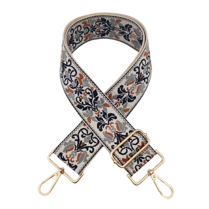 Detailed view of ethnic embroidery pattern on wide bag strap with golden metal clasp