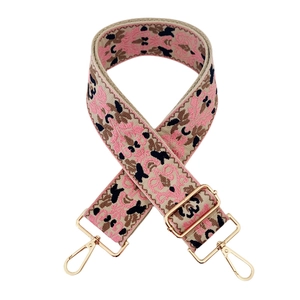 Close-up of ethnic embroidery bag strap with pink jacquard patterns and gold metal clips