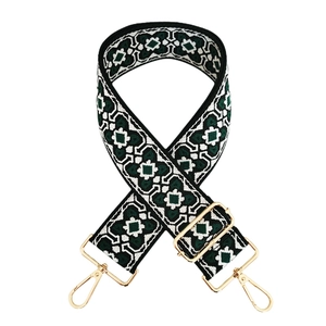 Detail of vintage geometric jacquard bag strap with polished gold-tone metal buckles