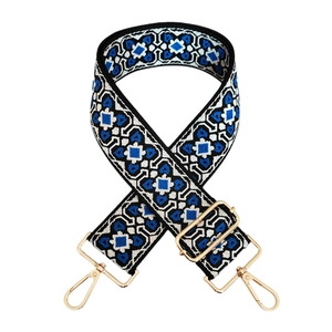 Detail of blue and white geometric jacquard bag strap with gold metal lobster clasps