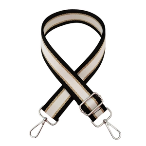 Close-up of black and white striped bag strap with gold threads and silver metal clasps