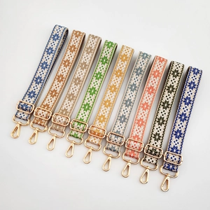 Detailed embroidery on woven bag straps with geometric ethnic patterns and gold metal hooks
