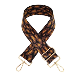 Détail d'une bandoulière léopard tissée avec des boucles en métal doré ajustables