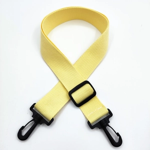 Detail of yellow canvas bag strap with black plastic swivel hooks and adjustable buckle