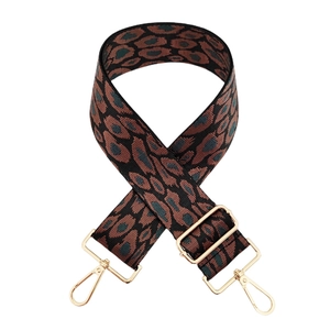 Detail of leopard print wide bag strap with gold metal buckles and thick jacquard fabric