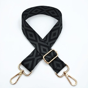 Close-up of geometric diamond pattern embroidery on adjustable wide bag strap with gold buckle