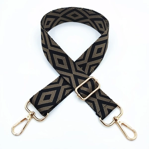 Detail of adjustable black and gold geometric embroidered bag strap with metal lobster clasps
