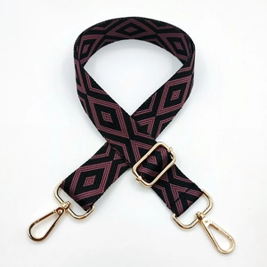 Close-up of purple geometric diamond embroidery on bag strap with gold metal swivel hooks