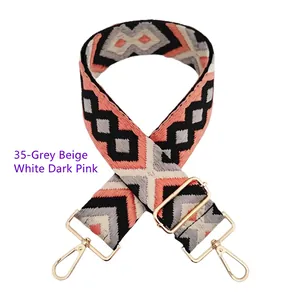 Detail of grey and dark pink woven wide shoulder strap with golden metal swivel hooks
