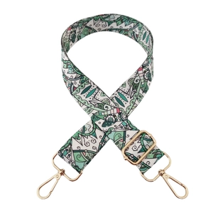 Close-up of green geometric pattern bag strap with polished gold metal buckles