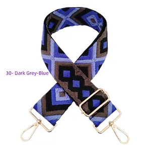 Detail of blue and grey geometric embroidered bag strap with golden metal lobster clasps