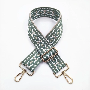 Detail of green ethnic jacquard bag strap with gold metal lobster hooks and buckle