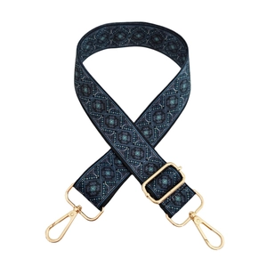 Detail of wide shoulder strap featuring blue geometric pattern and gold metal hardware