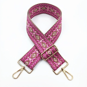 Close-up of ethnic jacquard purse strap with pink geometric patterns and gold metal hooks