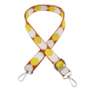 Close-up of adjustable woven strap with orange yellow polka dots and metal lobster clasps