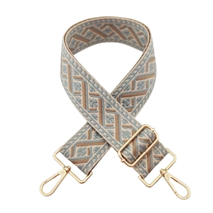 Detail of wide woven strap with geometric patterns and gold metal lobster clasps