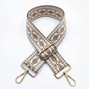 Detail of bohemian geometric jacquard bag strap with golden metal hardware adjusters
