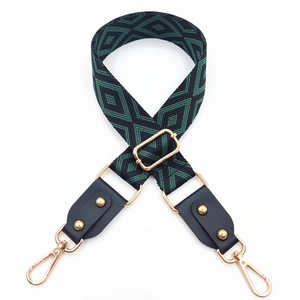 Détail d'une bandoulière jacquard géométrique vert et noir avec mousquetons dorés
