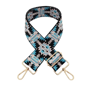 Close-up of ethnic style wide polyester bag strap with jacquard embroidery and gold hardware
