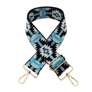 Macro detail of bohemian geometric embroidered bag strap with gold metal lobster clasps