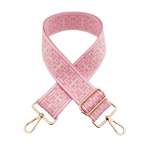 Detail of pink and white jacquard bag strap with geometric patterns and gold-tone hooks