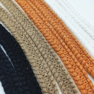 Detail of knitted shoulder strap with gold sequins in black, brown, orange, and white
