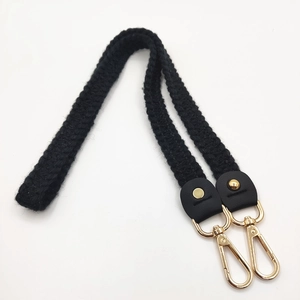 Detail of hand-woven black knit bag strap with gold rivets and lobster clasps