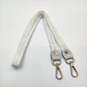 Macro detail of knitted shoulder strap with golden metal lobster clasps and leather ends