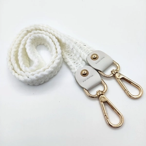 Detail of white knitted shoulder strap with silver sparkles and gold metal lobster clasps