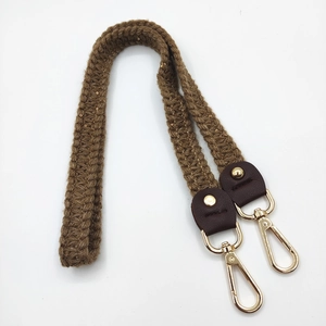 Macro detail of dark brown knitted shoulder strap with leather patch and gold metal clasps